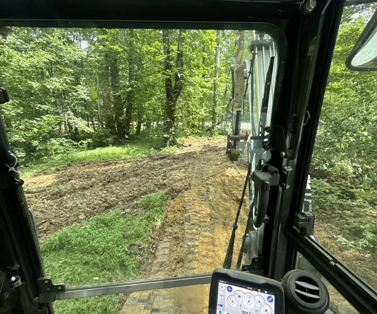 View from the operator's seat of a machine cab looking out over a wooded land clearing job near Birchwood, TN