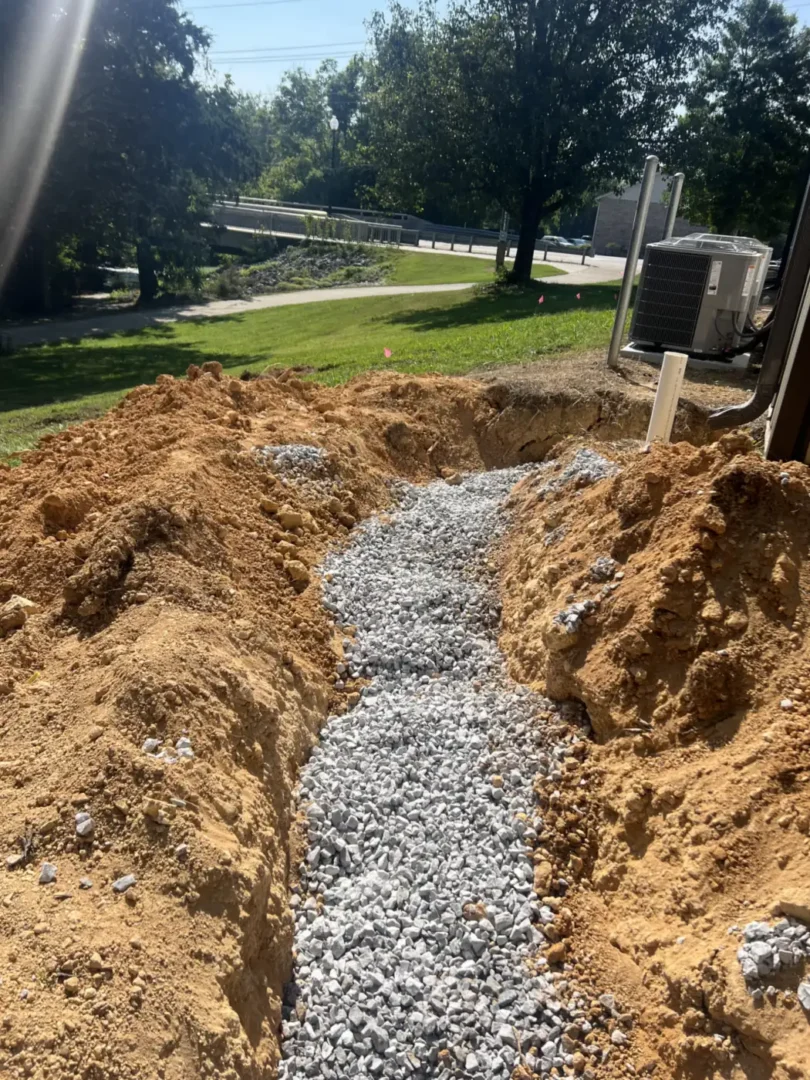 New Septic Installation: a gravel-bedded drain line trench dug beside a residential driveway near Chattanooga, TN